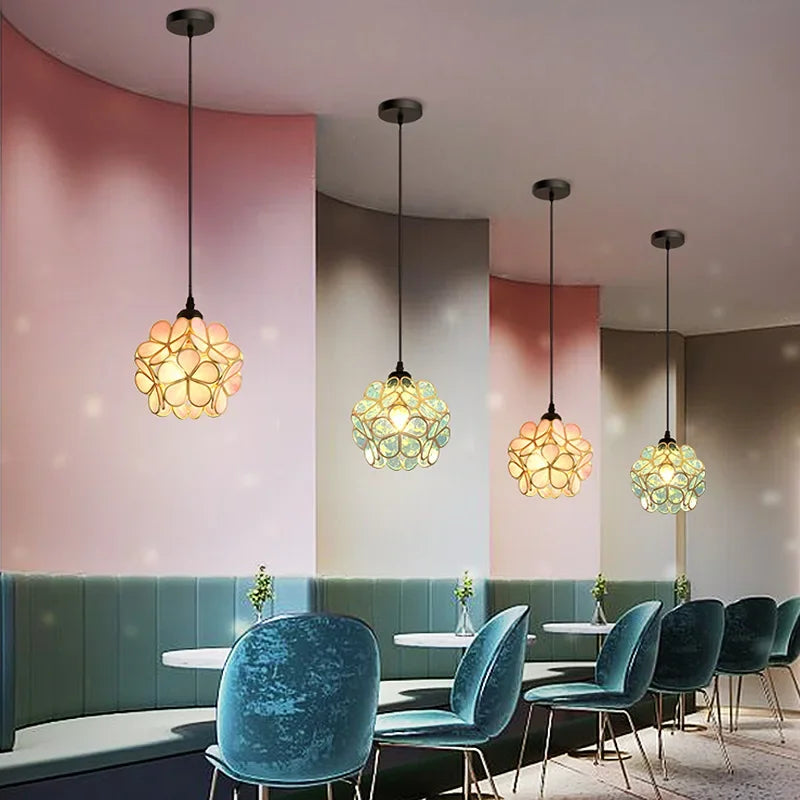 Four nordic modern petal acrylic pendant lamps with spherical flower-like amber and teal glass shades hanging indoors