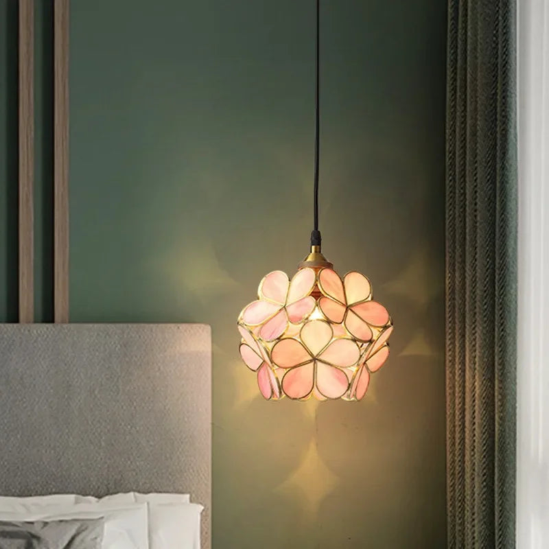A delicate pink and peach floral stained glass Nordic modern petal acrylic pendant lamp suspended by a black cord
