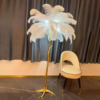 A tall elegant floor lamp with a golden metallic base and white soft ostrich feathers for living room decor