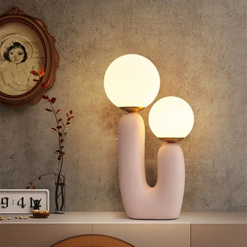 Pastel pink ceramic ball table lamp with two glowing glass ball shades and gold-toned accents for bedroom decor