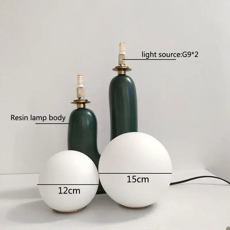 Two matte white spherical resin ball table lamps with dark green bases ideal for bedroom decor