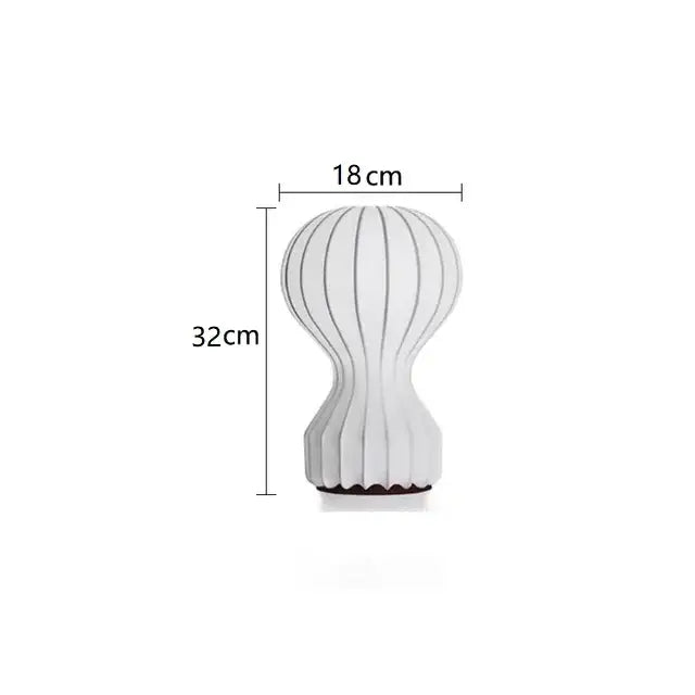 A sleek white ceramic nordic ribbed silk table lamp with hourglass shape and dark base for bedroom decor