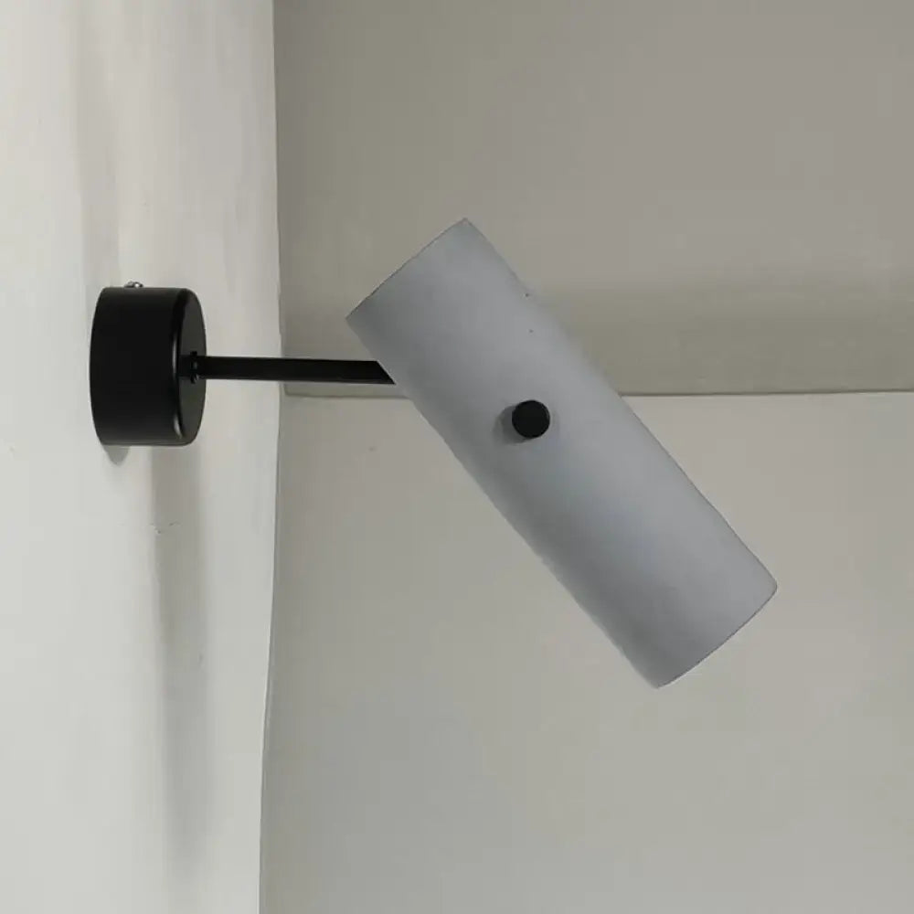 Nordic style matte black rotatable wall spotlight with a circular base and frosted white cylindrical diffuser for bedroom lighting