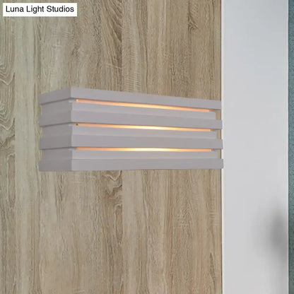 Modern white bedroom wall sconce with nordic style louvered design and three horizontal slats emitting warm ambient glow