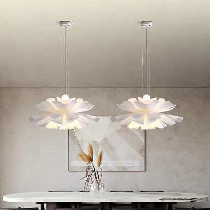 Two elegant white acrylic flower pendant chandeliers hang with layered design on slender metallic chains for bedroom decor