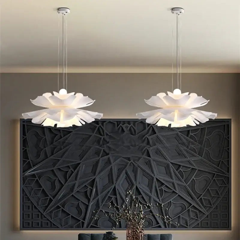 Two elegant white acrylic flower pendant chandelier lights hang symmetrically above a dark geometric wall panel