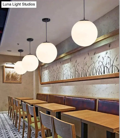 White spherical pendant lights with black fixtures in nordic white glass ball design for modern living spaces