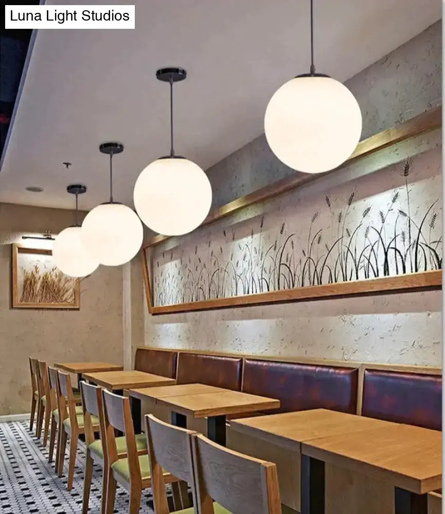 White spherical pendant lights with black fixtures in nordic white glass ball design for modern living spaces