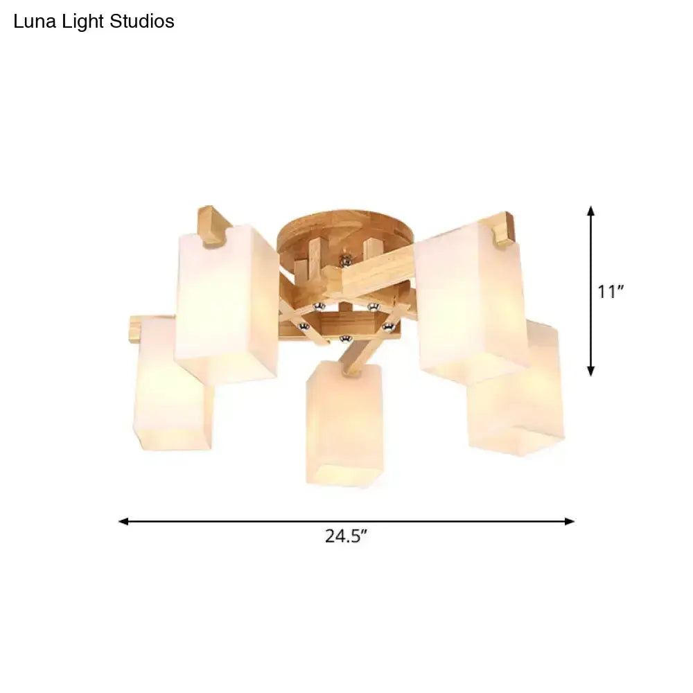 A modern ceiling lamp with a natural wood frame and five cuboid cream glass shades for living room use