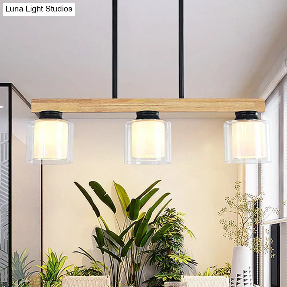 Modern farmhouse pendant light with natural wood beam and three clear glass shades for restaurant island lighting