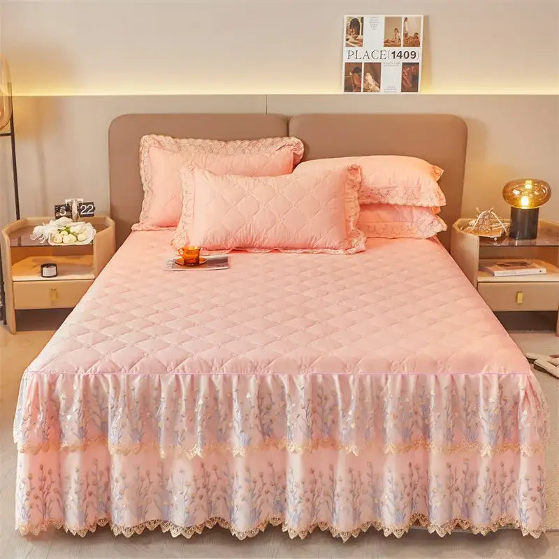 Pink quilted bed skirt with delicate lace trim and floral embroidery is shown as part of a bed skirt set