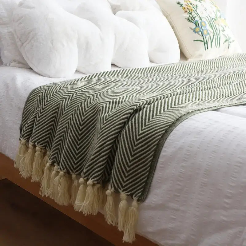 A soft olive green and cream decorbites geometric knitted blanket with herringbone pattern and fringed tassels for living room decor