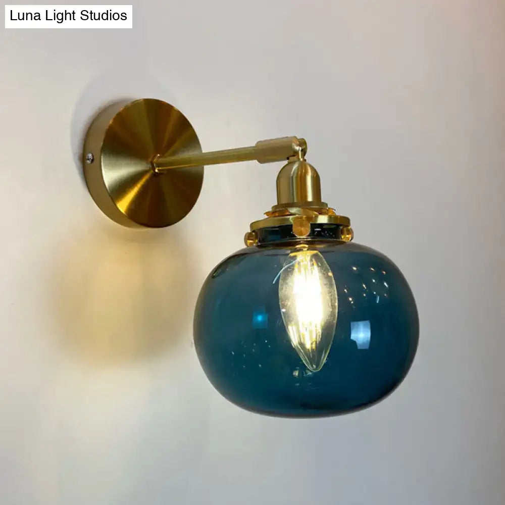 Blue glass globe wall lamp with brass hardware designed as a bedroom wall lamp for elegant bedroom walls
