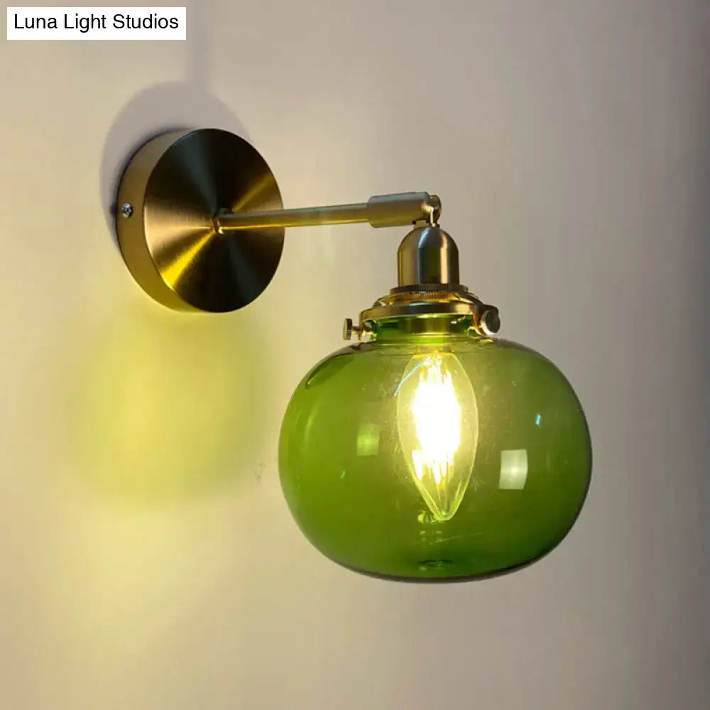 A vintage polished brass bedroom wall lamp with a green glass shade and exposed filament bulb for bedroom wall use