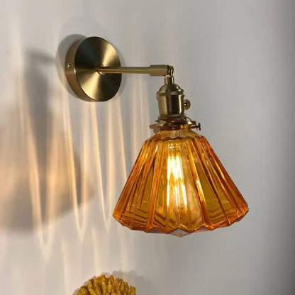 A warm amber glass wall lamp with fluted design and brass hardware for bedroom wall lamp use