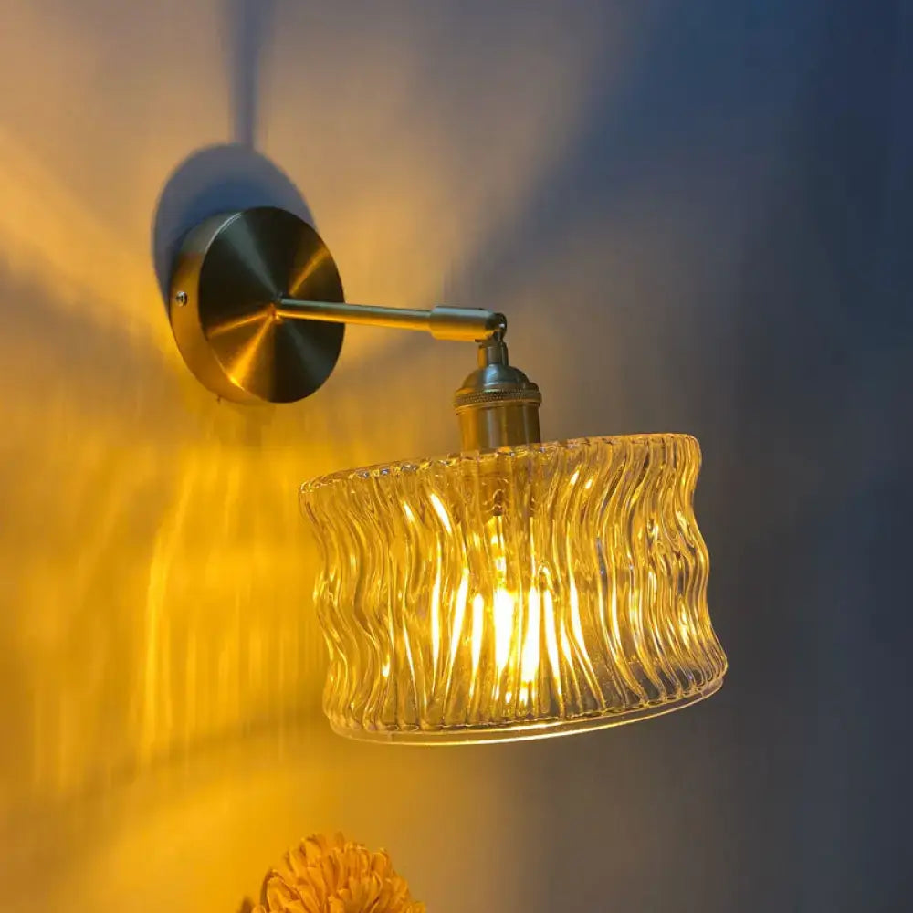 Orange and gold fluted glass wall lamp with warm-toned wavy texture and brass arm for bedroom wall lamp use