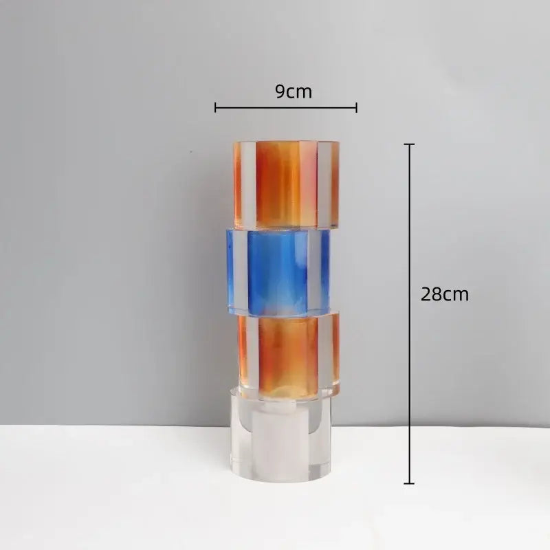 A modern clear crystal mosaic vase in gradient orange and blue acrylic serving as a living room candle holder