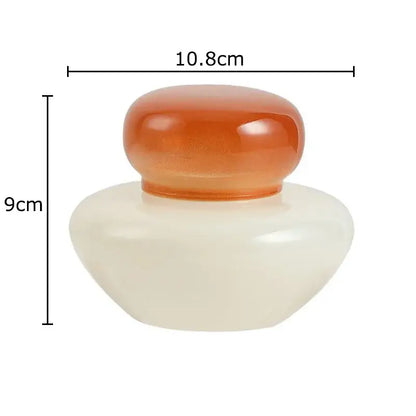 Cream-colored smooth ceramic glass storage jar with translucent amber glass lid from orange and blue glass storage set
