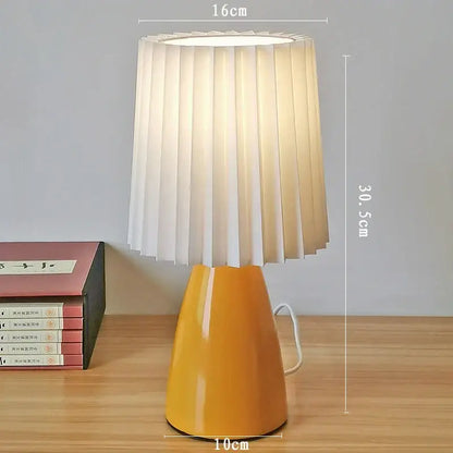 A warm yellow decorbites ceramic milkshake bedside lamp with pleated white fabric shade for bedroom decor