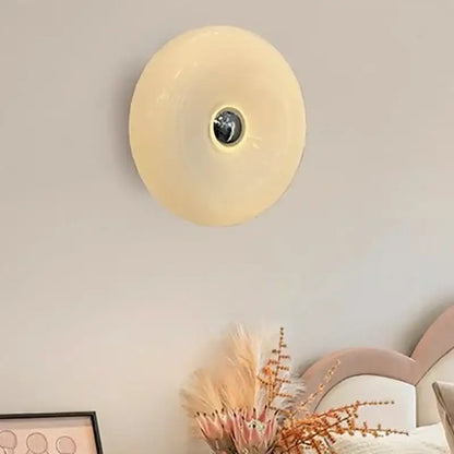Cream-colored circular wall sconce with central metallic fixture decorbites glass donut led for bedroom lighting