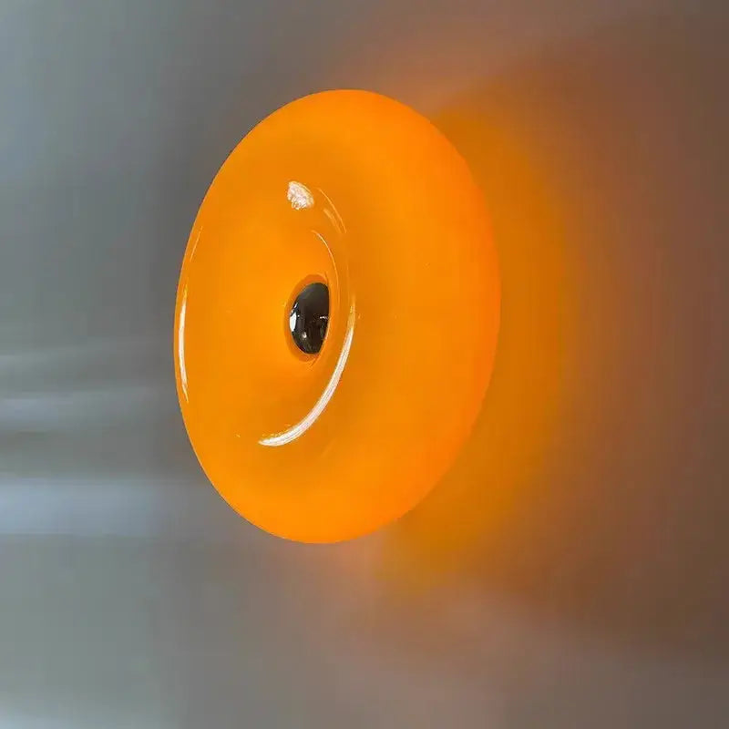 Orange glass donut led wall sconce featuring vibrant glossy glass donut with central black detail for bedroom lighting decorbites glass donut