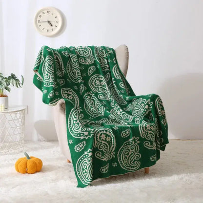 Green and white knit throw blanket with decorbites cashew pattern draped over chair for living room use