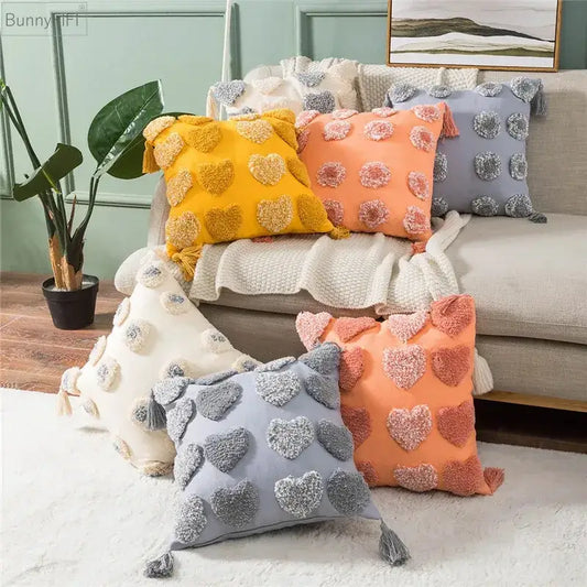 Cozy plush cushion covers in vibrant orange and grey with decorbites heart embroidery, tassels, and pom-pom accents