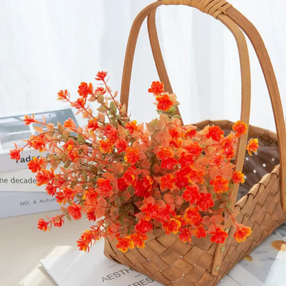 A vibrant orange and yellow artificial eucalyptus leaves arrangement in a woven wicker basket for garden decor