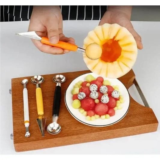 Orange stainless steel mini ball digger kitchen tool with orange handle scooping a mini ball from carved cantaloupe