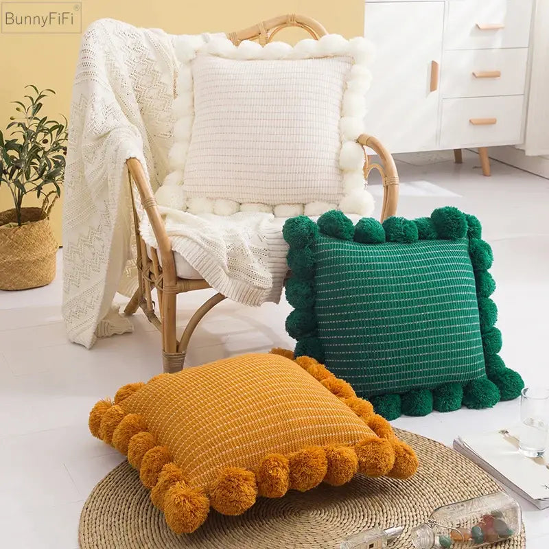 Three cozy textured ball cushion covers in mustard yellow forest green and cream with pompom trim for living room decor