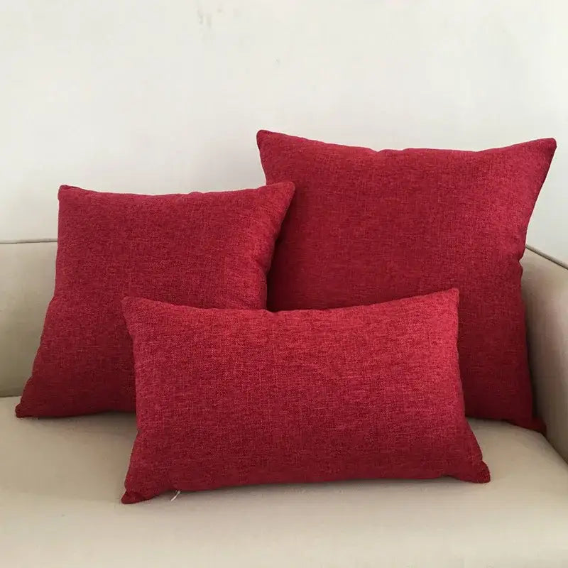 Three red textured linen cushion covers arranged on a light decorbites ivory sofa cushion for living room decor