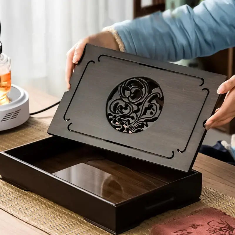 Dark wood tea box with ornate circular cutout lid design on black bamboo tea tray for dining room storage and drainage