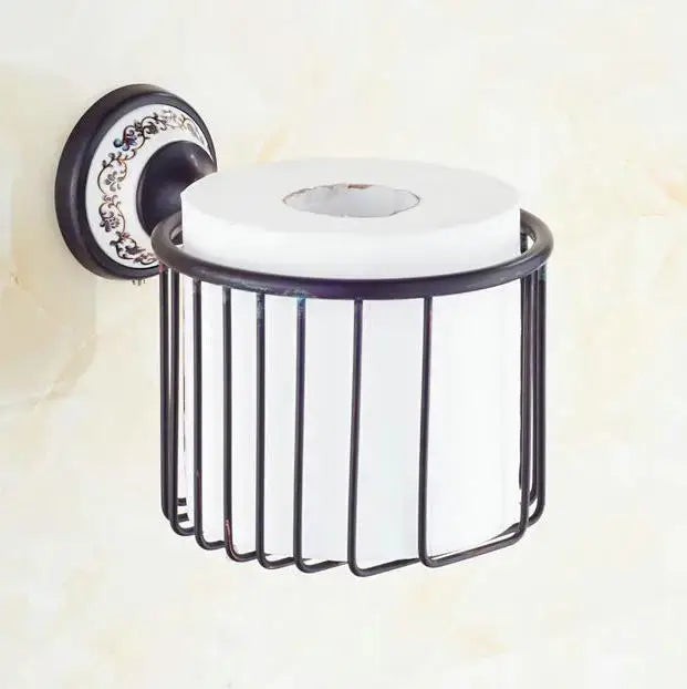 Ornate black wrought iron toilet paper holder with decorative plate and white roll in bathroom accessories set