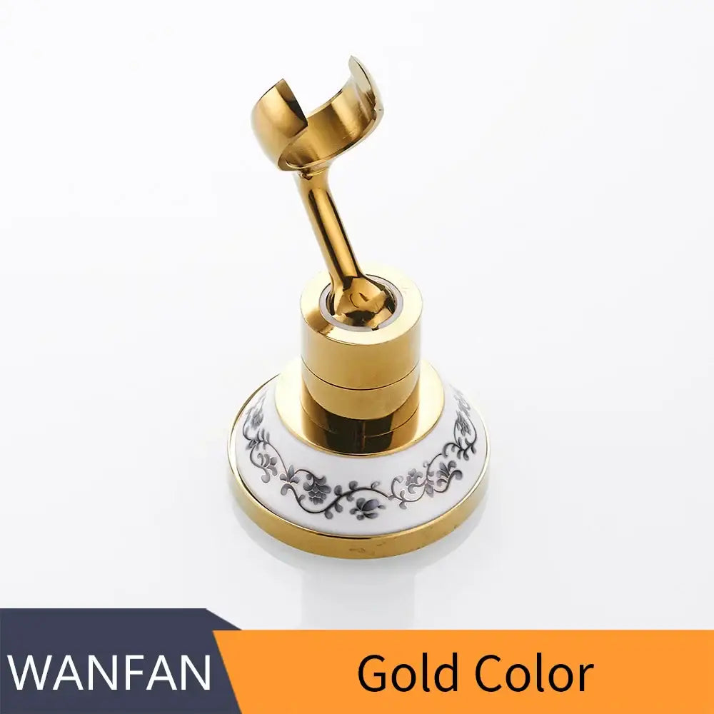 Gold-colored metal shower mount bracket with ornate black and white ceramic base for handheld shower accessory
