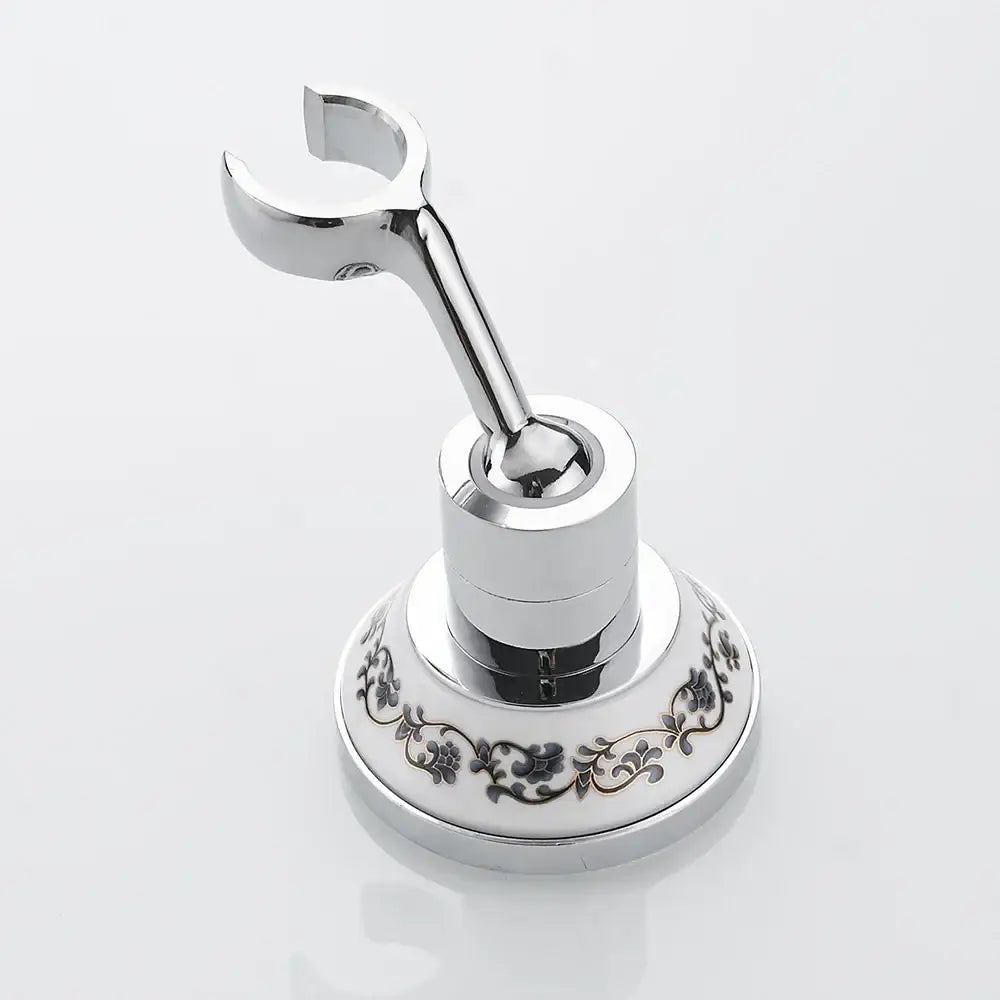Chrome-finished bathroom towel rack with ornate white ceramic base and black floral patterns for handheld shower mount bracket