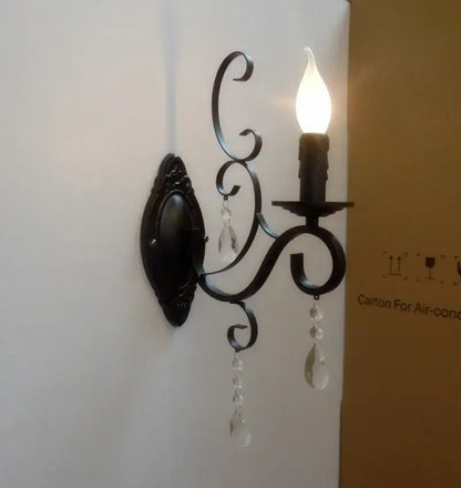 Ornate black wrought iron wall lamp with crystal droplets and candle-style bulb for living room decor by decorbites black wrought