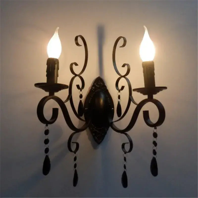 Ornate black wrought iron wall lamp with two candle bulbs and teardrop crystals for elegant living room decorbites black wrought design