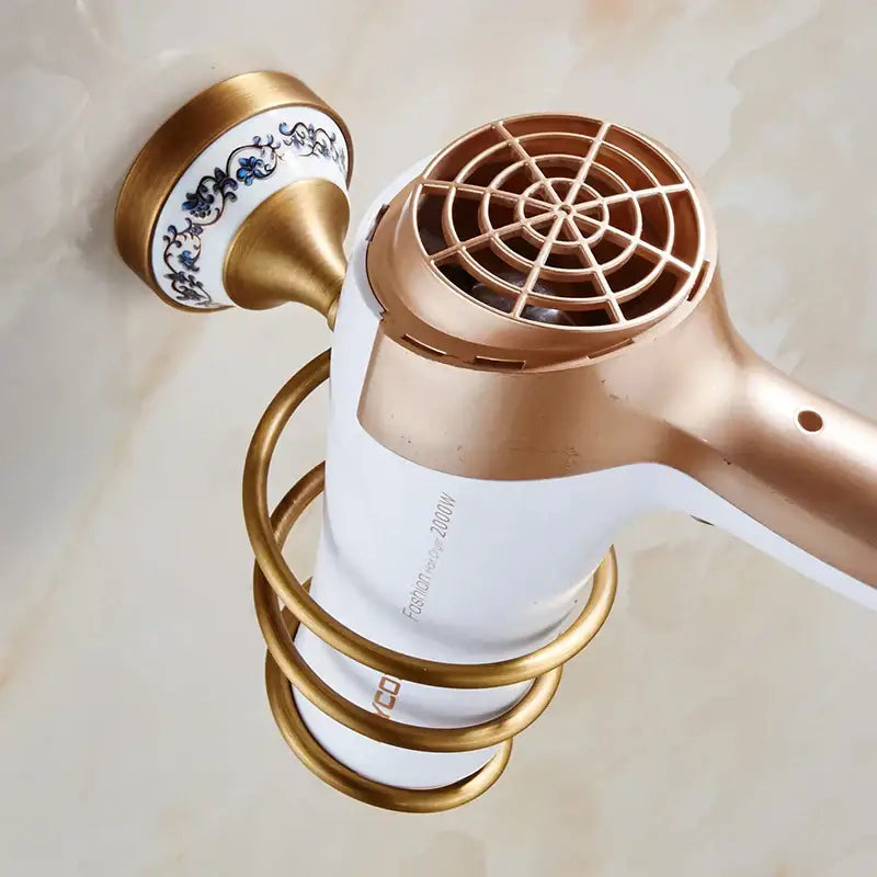 Gold-toned ceramic and metal hair dryer holder with blue floral pattern in ornate brass and white ceramic bath hardware set