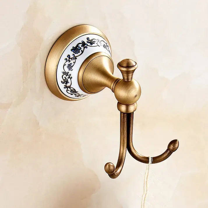 Antique brass double hook with white ceramic backplate and blue floral patterns in ornate bath hardware set