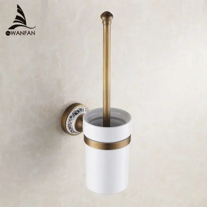 Antique brass-finished toilet brush holder with white ceramic cup and floral mounting plate in bath hardware set