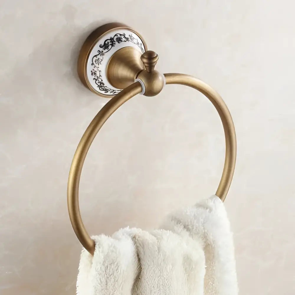 Antique brass towel ring with black floral ceramic backplate in ornate brass and white ceramic bath hardware set
