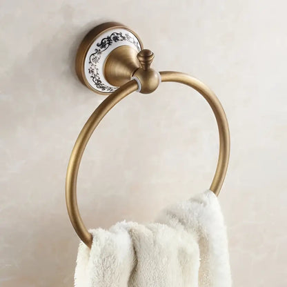 Antique brass towel ring with black floral ceramic backplate in ornate brass and white ceramic bath hardware set