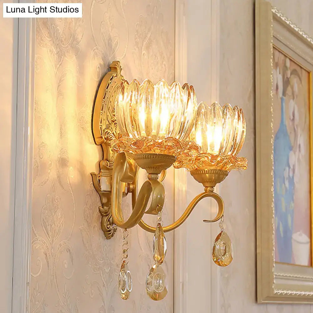 Ornate brass lotus wall sconce with gold tones, amber fluted glass shades, crystal pendants, and e14 bulb sockets
