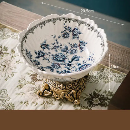Delicate white ceramic flower pattern fruit bowl with colorful floral design and scalloped rim on ornate gold stand
