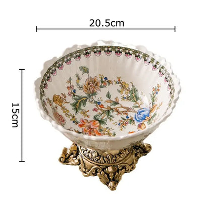 Ornate ceramic fruit bowl with a colorful flower pattern and scalloped rim on a gold metal stand for dining room use