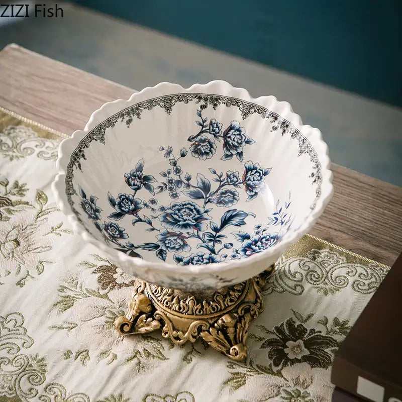 A delicate white porcelain flower pattern fruit bowl with intricate blue floral patterns on a gold-colored stand