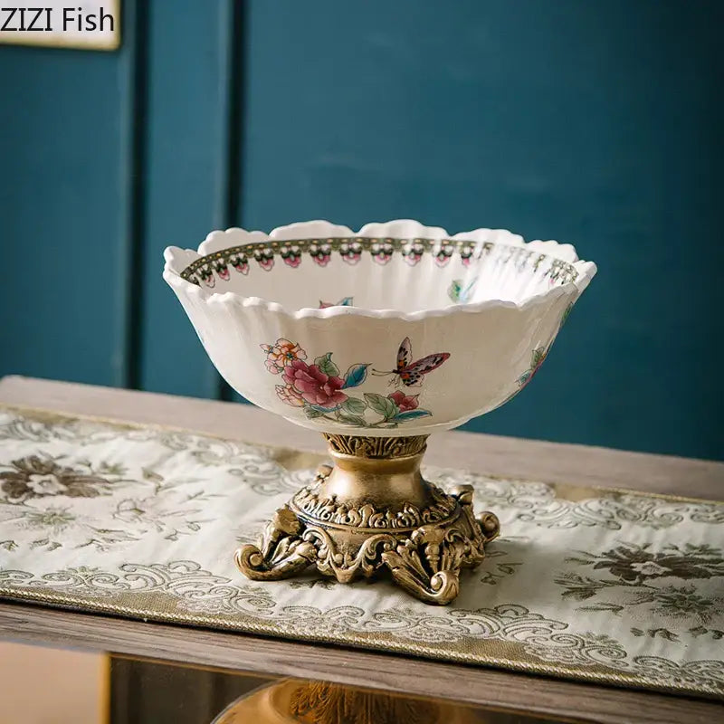 White ceramic pattern fruit bowl with colorful flower pattern and butterfly design on an ornate gold pedestal base