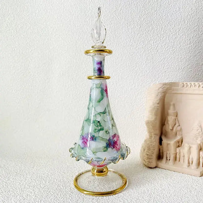 A delicate glass bottle jewelry ornament with a fluted base gold accents and hand-painted pink green florals