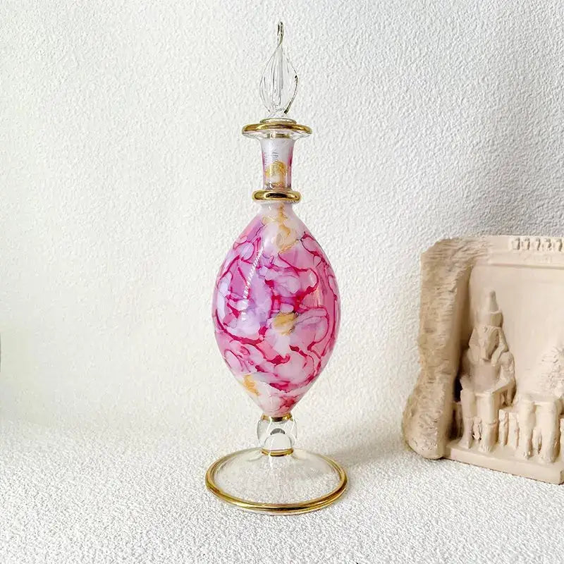 Ornate pink and white marbled glass bottle jewelry ornament with gold accents and elegant footed base for bedroom decor