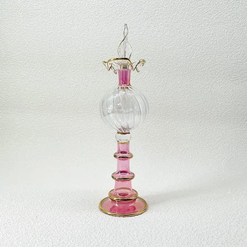 A delicate pink and clear glass bottle jewelry ornament with gold accents for bedroom decor featuring a twisted stopper